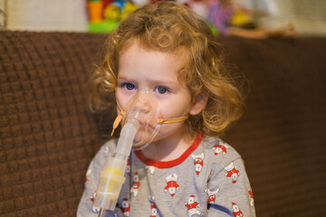 Young child, a girl, receiving nebulizer treatment at home. Pediatric healthcare for respiratory illness and asthma. Child health concept.