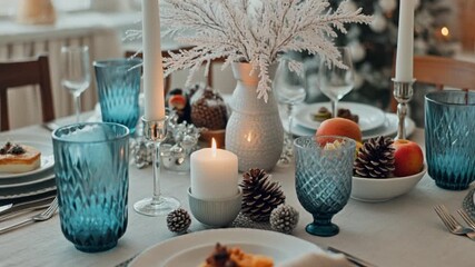 A festive wedding or holiday dinner table setting is decorated with plates, glasses, candles, and a flower bouquet - Powered by Adobe