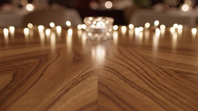 Wooden table adorned with string lights and a candle, warm ambiance, blurred background
