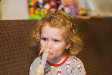 Young child wearing a nebulizer mask. Inhalation treatment for respiratory illness. Healthcare concept for kids with allergy or asthma.