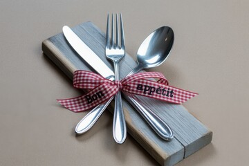 Elegant tabletop setting with silverware tied with a charming ribbon encouraging a delightful meal, perfect for culinary blogs and restaurant promotions