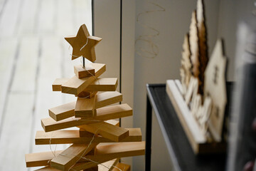 Naklejka premium Détail d'un sapin de Noël fabriqué en plaque de bois, placé devant une fenêtre, pour décorer un intérieur pour les fêtes de fin d'année