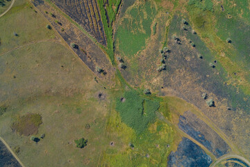 Vertical aerial photograph of a complex battlefield landscape featuring small shell impact craters, burnt ground, and mixed fields. Abstract pattern - conflict, war damage, and environmental impact.