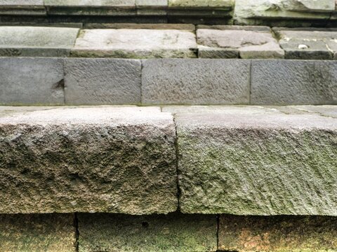 Historical stone masonry detail. Weathered, rough blocks form the steps or wall of an ancient temple, showing the effects of time and nature.
