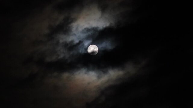 Full moon, at night, clouds moving slowly across the moon, dark night sky, real video