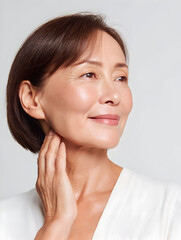 エイジングケア シニア女性が首元に触れながら先を見つめるナチュラルメイクのマチュアビューティーポートレート