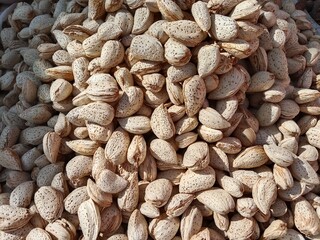A neat pile of almonds (Prunus dulcis) displayed for sale in the market, dry brown seeds with natural texture, healthy snack concept, organic food and agriculture product background