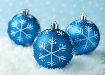 Closeup of several shiny blue christmas ornaments with snowflake patterns on a light blue background