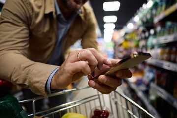 Close up of man checking his shopping list on smart phone at store.