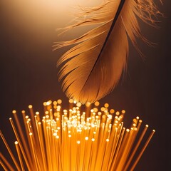 A close-up of a delicate feather positioned above a cluster of glowing fiber optic strands illuminated with warm, golden light in a dark environment