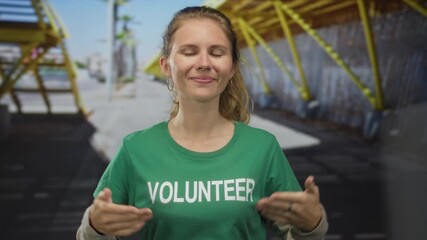 Woman wearing a shirt is pointing in a studio at volunteer blonde young wearing a tshirt and green earring.