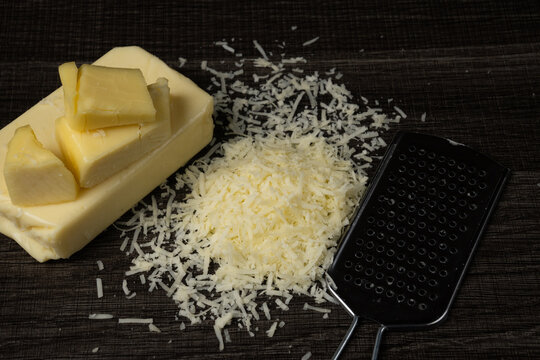 Freshly Grated Cheese and Grater on Wooden Surface