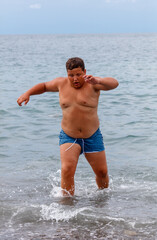 A man in a blue swim trunks is running in the ocean
