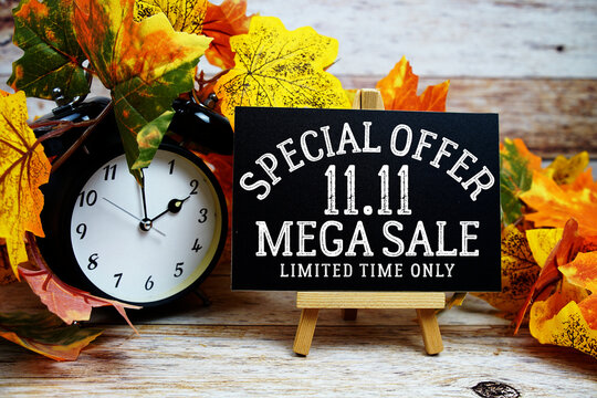11.11 Mega Sale Special Offer text with alarm clock and maple leaf decoration on wooden background
