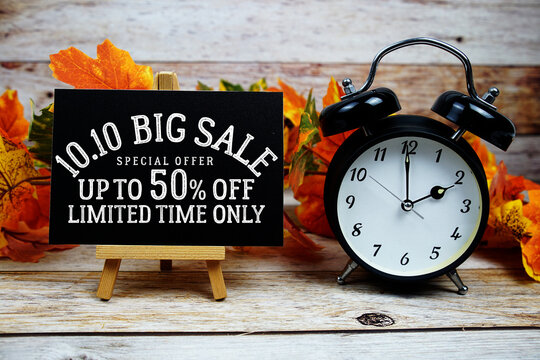 10.10 Big Sale 50% off Special Offer text with alarm clock and maple leaf decoration on wooden background - Powered by Adobe