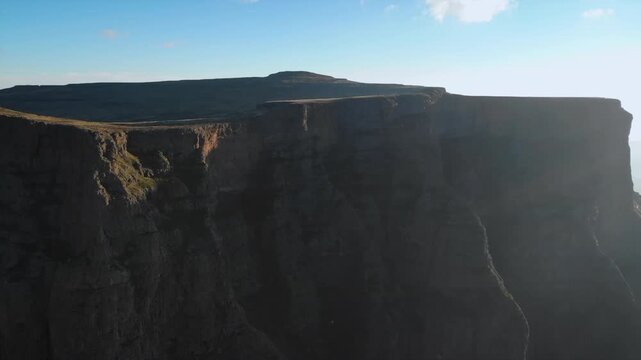 vertical cliff with exposed layers, high escarpment featuring exposed rock layers and vertical walls