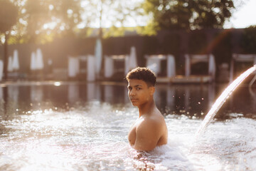 Young man relaxing in a luxurious hotel pool during sunset