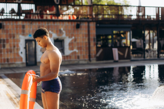 Lifeguard preparing rescue equipment by the poolside on a sunny day