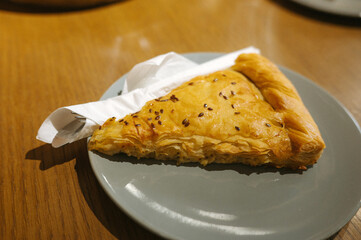Flaky pastry slice on plate with napkin on wooden table