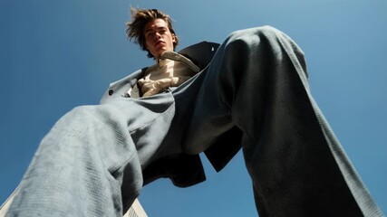 Low‑angle fashion portrait of a confident man in a tailored suit towering against city skyscrapers—bold style, ambition, street editorial energy, and modern menswear authority
