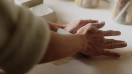 Hands at work shape ceramic creation in pottery studio