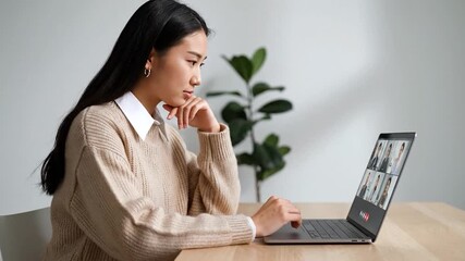 A woman in a video call. She looks at her laptop while resting her hand on her face - Powered by Adobe