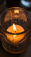 A close-up view of a lit candle inside an ornate glass holder, casting a warm glow and creating a cozy ambiance suitable for relaxation or meditation