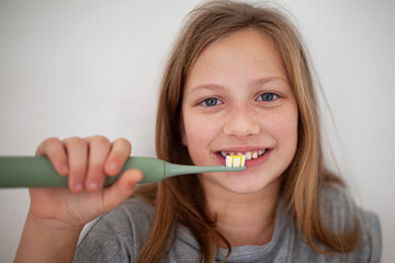 Preteen girl brushing teeth in natural lifestyle scene