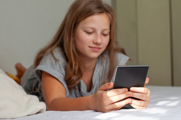 Teen Girl Reading an E-Reader in Bed