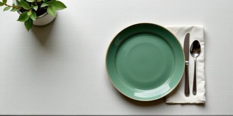 Minimalist dining setup with a green plate, silverware, and a small plant.