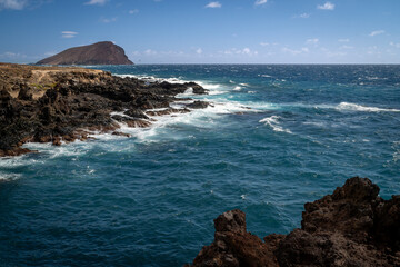 Rocky coastline and turquoise waves on the south coast of Tenerife. Dynamic ocean, volcanic cliffs and clear skies create a vibrant Atlantic landscape.