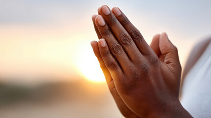 Hands are clasped together in gesture of prayer or meditation, symbolizing peace and reflection. This evokes sense of mental clarity, health, and wellness as sun sets in background
