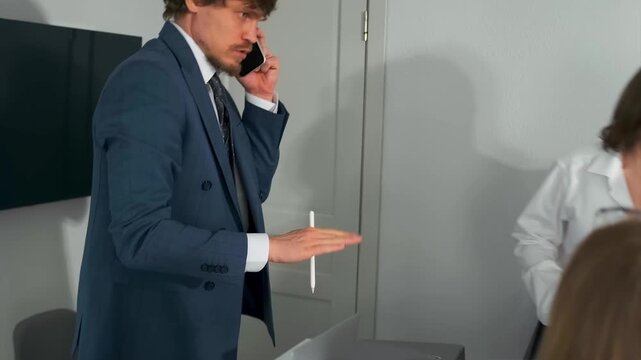work conflict intensifies, tense exchange in office escalating over urgent phone call and gestures, office disagreement heightens during tense phone call with hurried gestures and authoritative