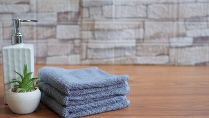 Soft pink towels, stacked black spa stones, and a liquid soap dispenser on wooden background create...