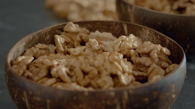Fresh walnut kernels are displayed in rustic bowls, showcasing their nutritious appeal and healthy fats. Perfect for snacking or adding to meals.