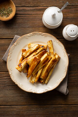 Top view of Honey roasted parsnips slices with herbs wooden table