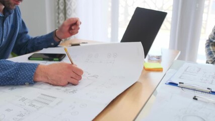 focused white architect unrolling large blueprints at desk with laptop magnifier and sketches, studying measurements and marking revisions, bright studio light and professional planning atmosphere - Powered by Adobe