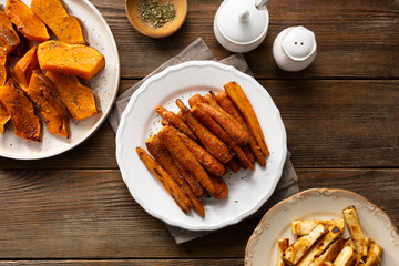 Oven baked baby carrots parsnips roots  on wooden table top view