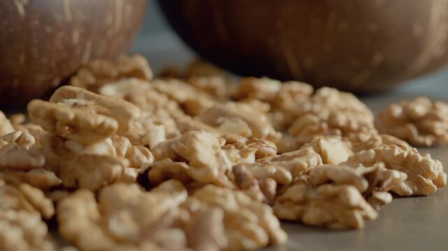 Fresh walnut kernels are scattered on a table next to rustic bowls. The setting is warm and inviting, showcasing the beauty of natural ingredients.