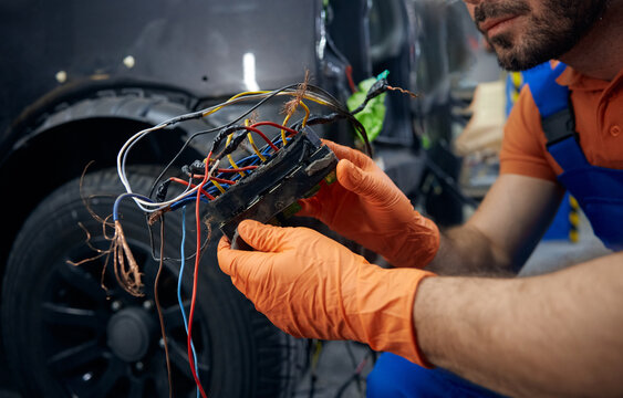 Mechanic inspecting complex car wiring harness in garage