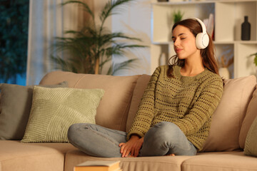 Woman in green relaxing listening audio on headphone in the night