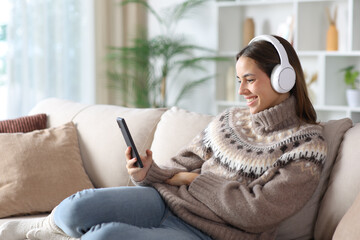 Happy woman in winter watching media on smart phone