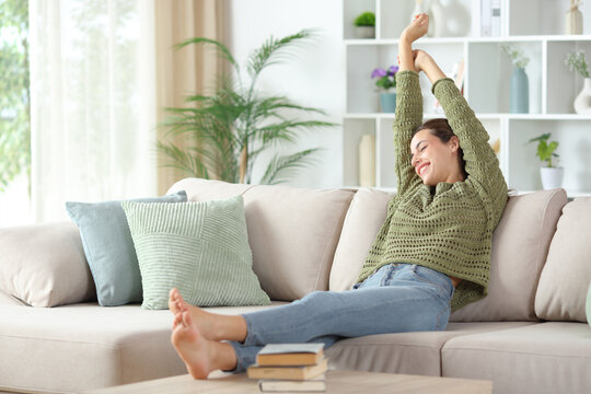 Happy woman stretching arms after napping on a couch
