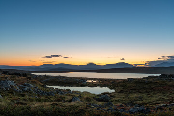 A colorfull sunset and the lake Várddoaijávri (Varddoaijavri) in the highlands of Utsjoki in the Finnish Lapland with the view to the high fells on the Norwegian side of the border