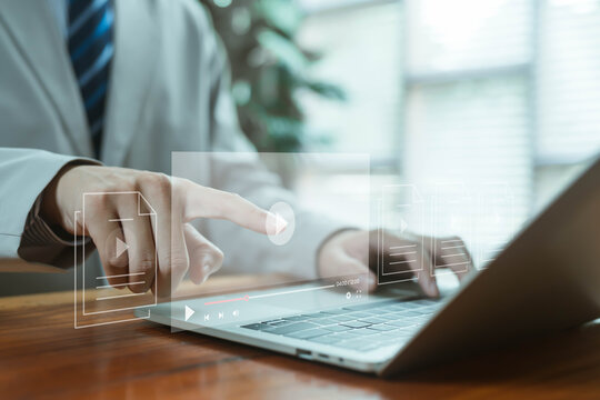 A futuristic digital video interface displayed above a laptop as a hand taps the play icon, symbolizing online media creation, streaming technology, file management, and modern content production