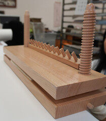 Wooden bookbinding press on the table. Screw racks and a rack with pins, view in the workshop, close-up.