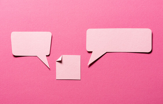 Speech bubbles and paper memo notes with folded dog-ear earmark and copy space for text on pink background, communication dialog concept top view flat lay
