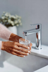 Person filling drinking glass with fresh tap water