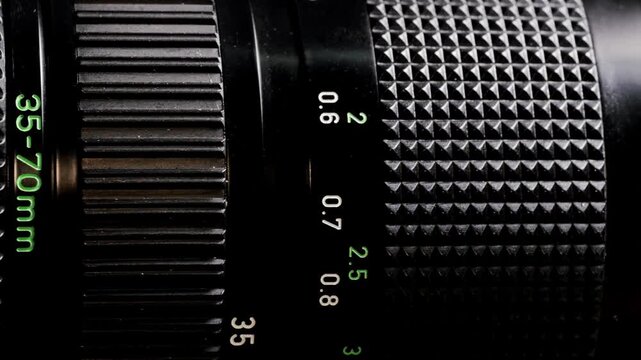 Rotating vintage 35mm to 70mm zoom camera lens lying flat with knurled rings
