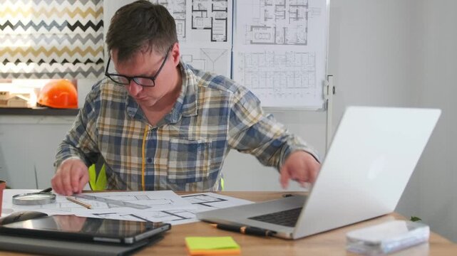 engineer closely examining technical blueprints with precise measurement tools nearby, white engineer diligently revising technical drawings at desk using magnifier and measuring instruments